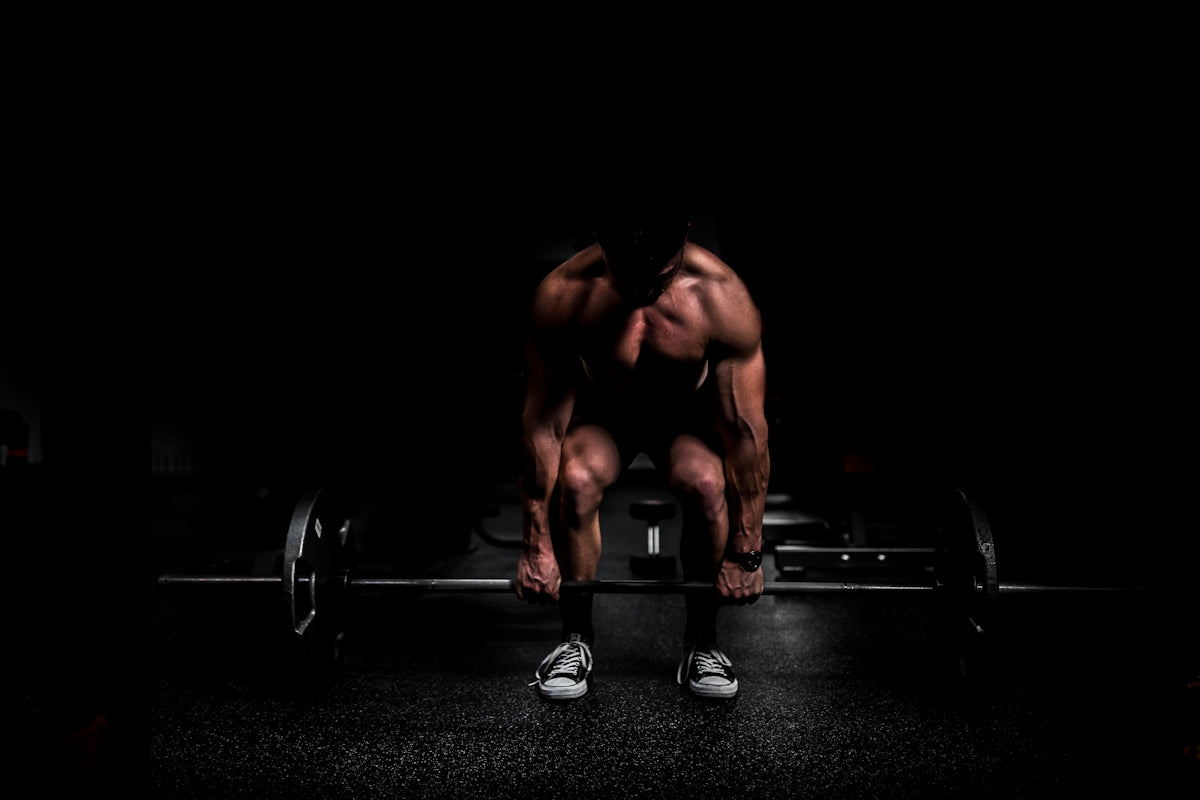 shirtless man lifting barbell in gym